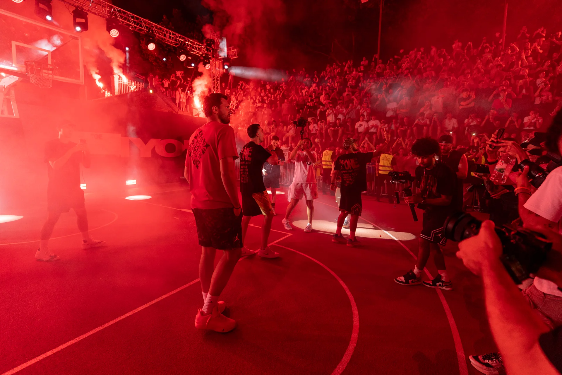 Crowded basketball court lit by red spotlights and smoke at Jordan The One in Belgrade