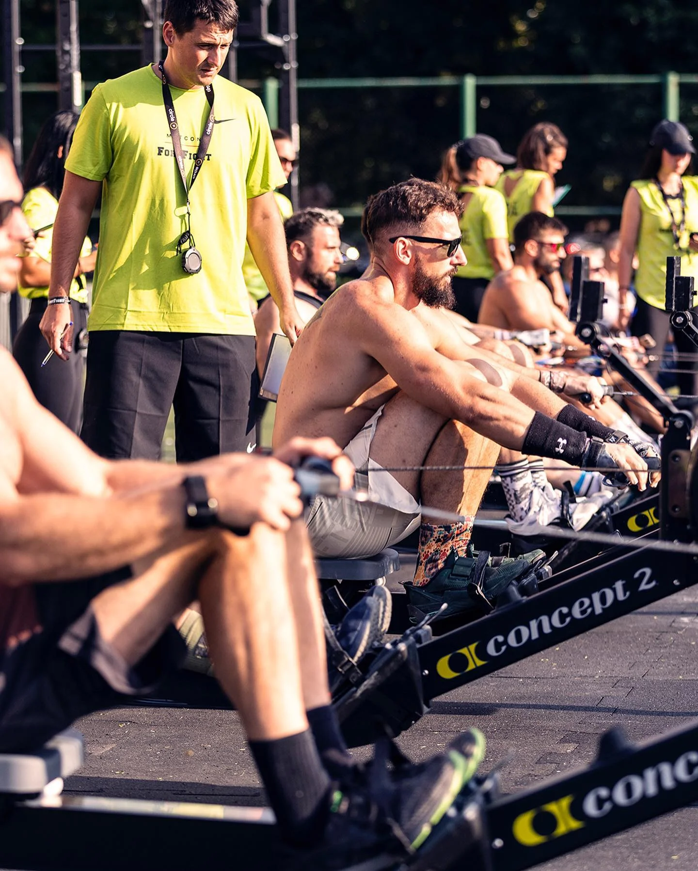 Athletes racing on rowing machines beside a judge at Nike Metcon FortFight