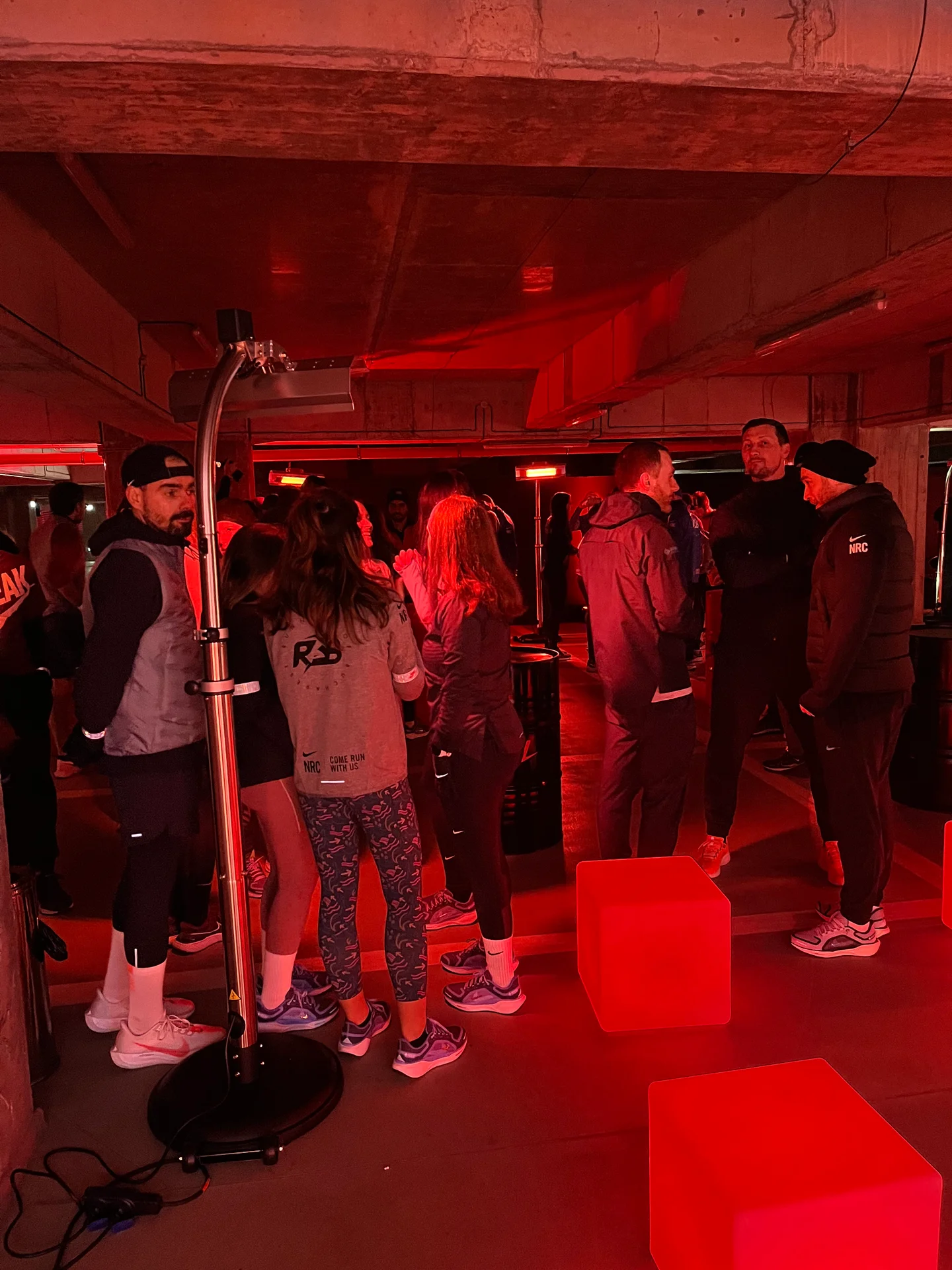 Runners gathering beside heaters under red lighting at Nike Midnight Run in Bucharest